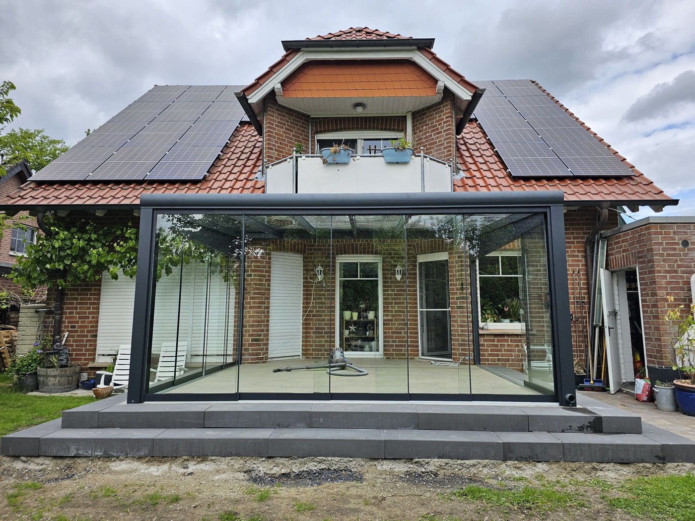 Wintergarten mit Glasschiebewänden an einem Backsteinhaus
